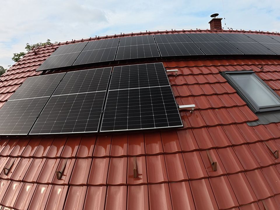 Fotovoltaické panely na červené pálené střeše rodinného domu, pohled z dronu