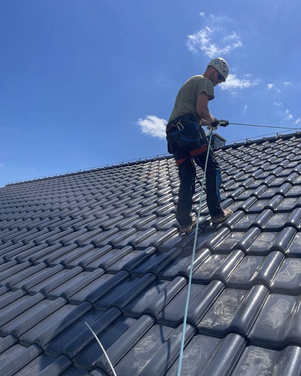 Technik v postroji natahuje jímací vedení hromosvodu na střeše novostavby