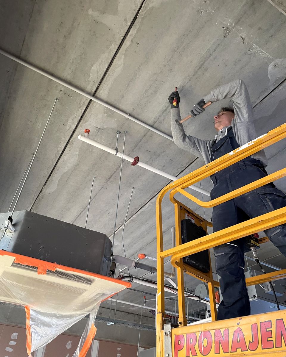 Technik na plošině montuje kazetové jednotky pod strop